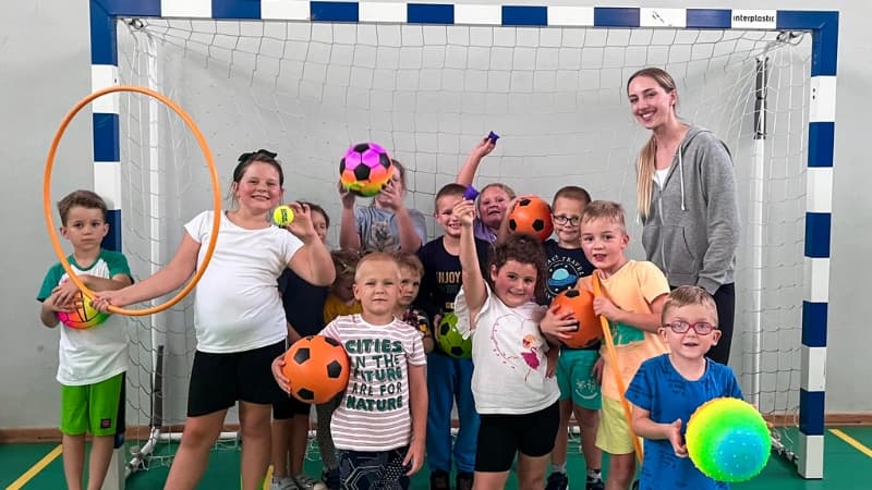 Aleksandra Zelewska z małą grupą dzieci podczas zajęć, pokazująca troskę i zaangażowanie